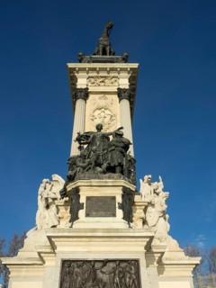 Imposing equestrian statue with detailed reliefs on a tall monument, Madrid, Spain, Europe