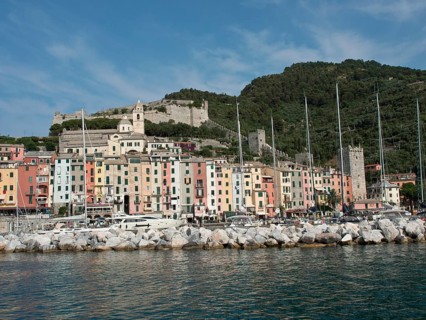 Colourful houses and boats in the harbour, historic buildings and calmly flowing water under a blue