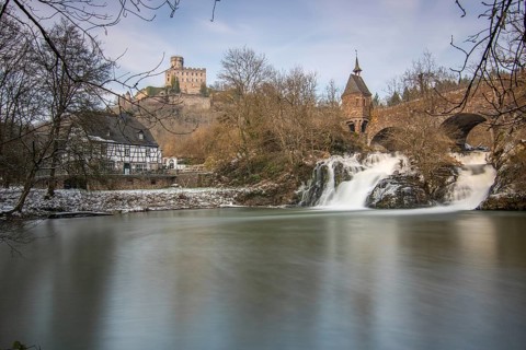 Beautiful landscape in winter with ice and snow. Waterfall of the river Elz near the castle