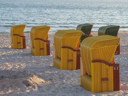 Yellow beach chairs on a sandy beach with a view of the sea in calm light conditions, autumn