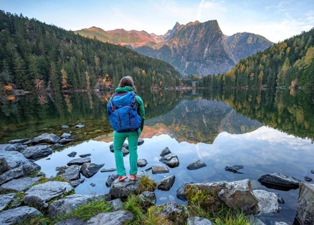 Hiker at the lake, mountain peaks of the Oetztal Alps are reflected in Lake Piburger See, in