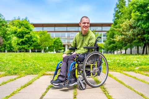 Full length portrait of a disabled man with cerebral palsy in the university campus