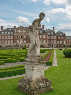 Sculpture in a well-kept garden with a baroque castle in the background, blue sky with clouds,