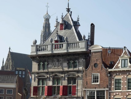Historic buildings and a church with a hotel in the foreground under a clear blue sky, Haarlem,