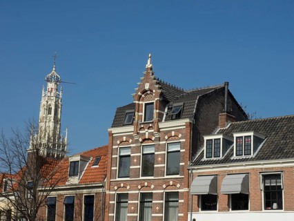 Beautifully decorated historic buildings and a magnificent church tower under a clear blue sky,