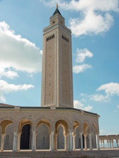 High minaret of a mosque in front of a clear blue sky, Tunis in Africa with ruins from Roman times,