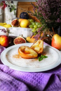 A rustic still life of fruits including pears, figs, and grapes, accented with spices and a bouquet