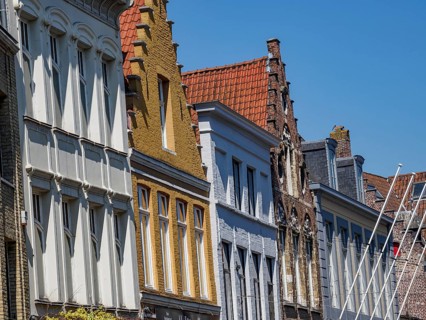 Row of historic buildings with ornate gables under a clear blue sky, historic houses and churches