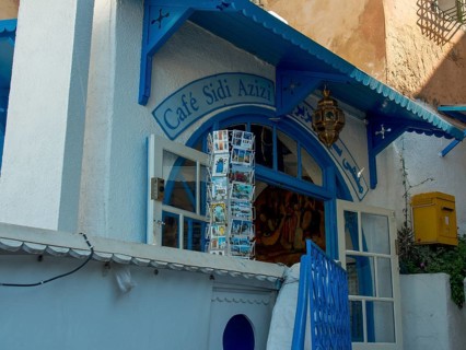 Traditional cafe with blue and white facade, postcard stand and lantern, cosy atmosphere, Tunis in