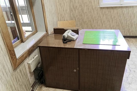 Abandoned, old-fashioned desk with telephone. Illuminated window and wooden panelling on the walls,