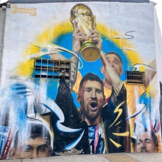 Street art mural by Maximiliano Bagnasco shows triumphant Lionel Messi with the World Cup trophy,