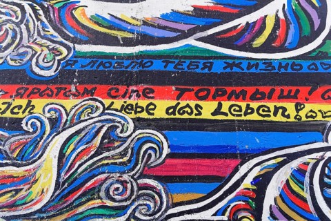 Colourful graffiti waves with texts in different languages on a wall, mural, East Side Gallery,