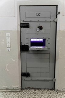 Close-up of a security prison door with food window and worn walls, Berlin-Hohenschoenhausen