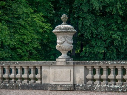 Stone sculpture in a well-kept garden, surrounded by a balustrade and green foliage in the