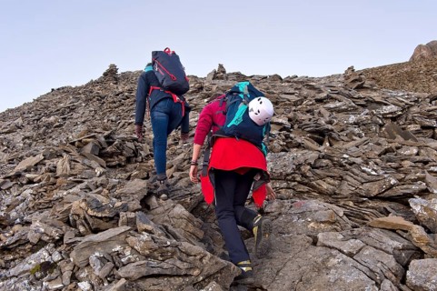 Two alpinists with heavy rucksacks climbing through a scree field, Bernese Alps, Kandersteg,