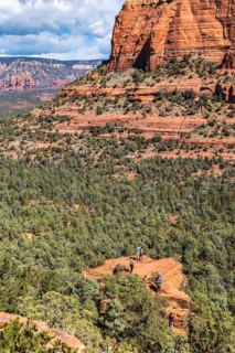 Hikers climb to the top of a red rock sandstone formation along the Devil's Bridge Trail in Sedona,