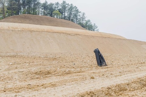 Black corrugated pipes protruding out of ground at rural construction site in Daejeon, South Korea,