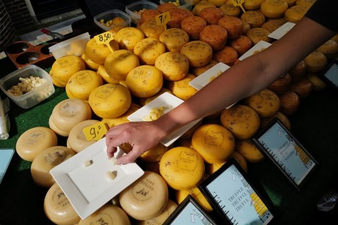 A person reaches to sample some Dutch cheese at a cheese market. Alkmaar, Netherlands