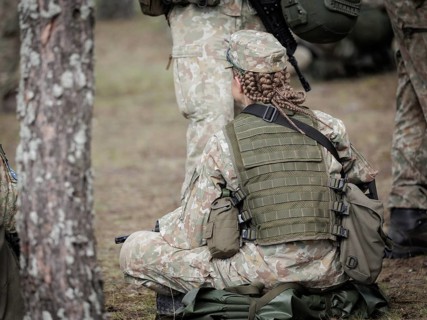 Young Lithuanian female reserve soldier sitting on the floor during her lunch break during her