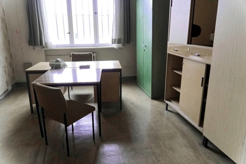 Simply furnished office with desk, chairs, filing cabinet and large window,
