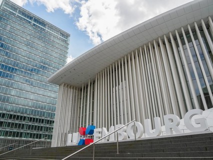 Modern building in Luxembourg with glass facade and striking columns next to a skyscraper, under a