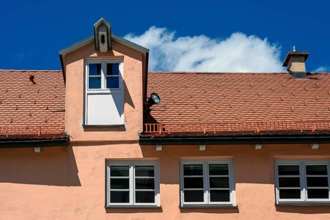 Red facade and tiled roof with crane dormer in the Muehlberg ensemble is a heritage-protected group