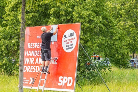 A poster artist renews a large SPD campaign poster for the elections on 8 June 2024, in the city
