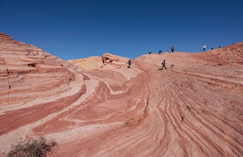 Park visitors on the layered sandstone rock formations in the Fire Wave area of Valley of Fire