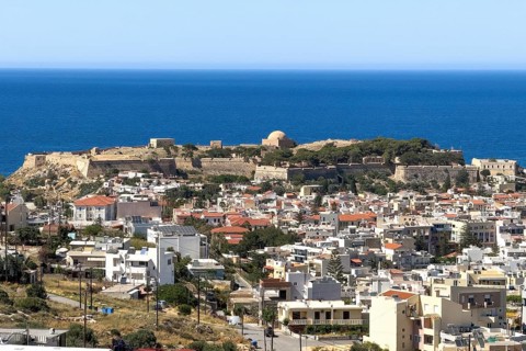 View from elevated position over rooftops of city of Rethymno on fortress walls and ruins of