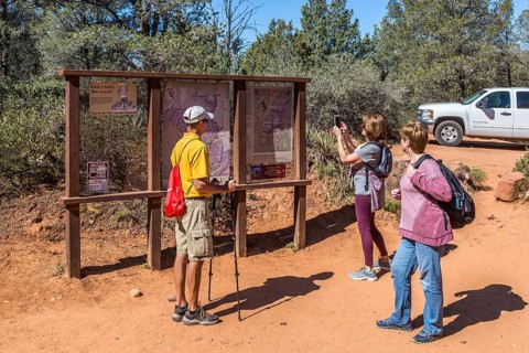 Woman takes photo of trail map before starting a hike in Sedona, Arizona, USA, North America