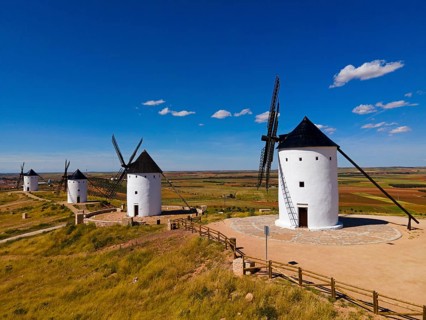 Grouped windmills on a hill under a bright blue sky in a vast summer landscape, aerial view,