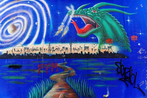Mural shows a dragon above a skyline at night, surrounded by a lake, stars and spiral pattern,