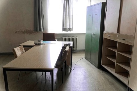 An office with simple furniture, desk, chairs, filing cabinet and a window,