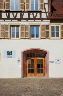 Detail half-timbered house, entrance, door with wood and glass, windows, shutters, sign for