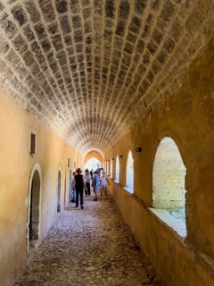 Archway with left doors to former monastery cell monk cells in the background tourists in UNESCO