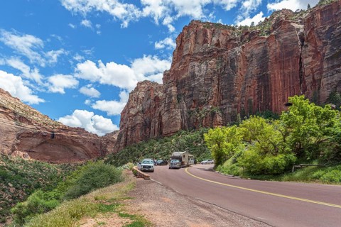 Recreational vehicle passes tourists at an overlook next to a blind arch along the Zion Park