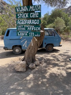 Tourist humorous funny sign on tree behind old Volkswagen VW Bus Bulli in front of entrance of