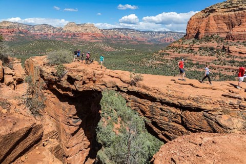 Hikers cross the Devil's Bridge natural arch along the Devil's Bridge Trail in Sedona, Arizona,