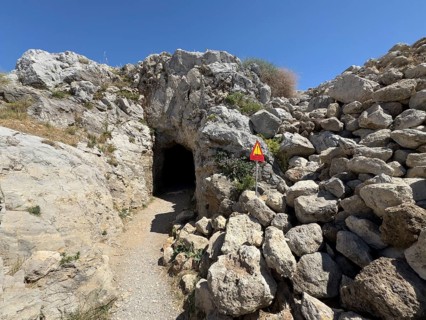 Entrance of a developed cave next to a warning sign warning of falling rocks on the site of the