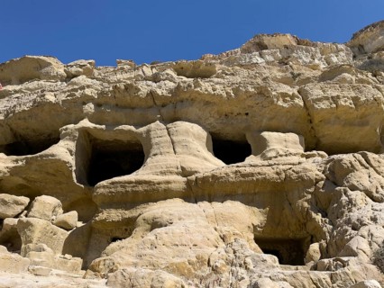 View upwards to sandstone rocks at the edge of Matala bay with entrances to caves of former Roman