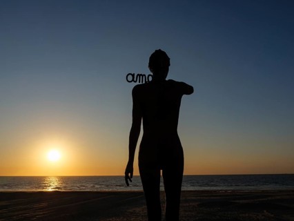 A silhouetted figure in front of a sunset on the beach, sunset in many colours on the beach with a