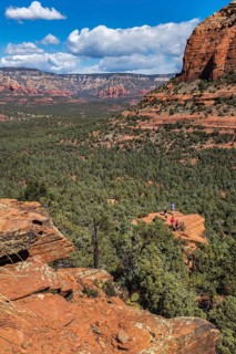 Hikers climb to the top of a red rock sandstone formation along the Devil's Bridge Trail in Sedona,