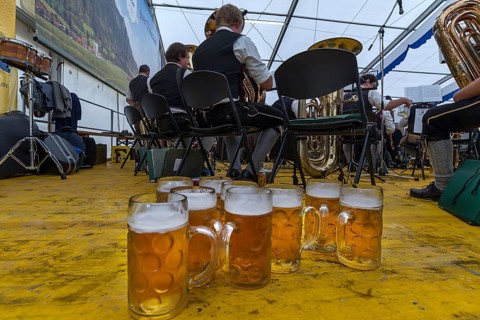 Full beer mugs on the stage of the musicians in a marquee, in the back the band, Bad Hindelang,