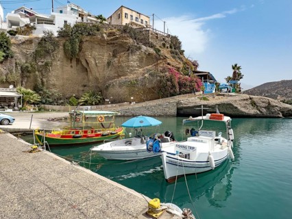 Three boats in small harbour marina of Agia Galini, right fishing boat ship excursion boat for