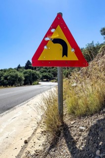 Bullet holes in road sign is target for target practice of bullets shot through, Crete, Greece,