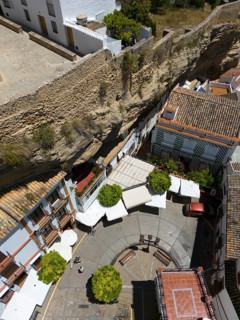 Aerial view of a Spanish village with narrow streets and stone wall, surrounded by buildings and
