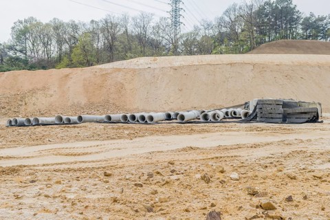 Concrete culvert pipes at base of dirt hillside at rural construction site in Daejeon, South Korea,