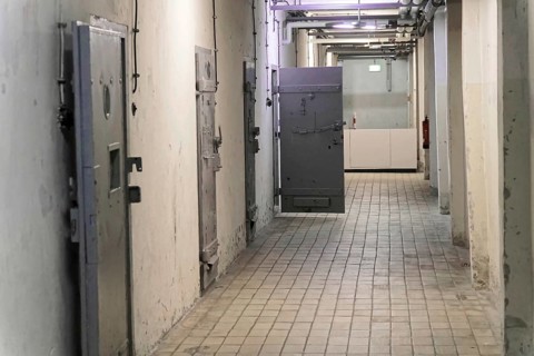 Corridor in a prison with metal cell doors and tiled floor. Gloomy and deserted atmosphere,