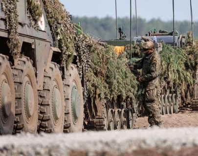 A Bundeswehr soldier works on the camouflage of a Cougar infantry fighting vehicle as part of the