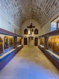 Entrance area with showcases and large wooden cross on wall in vaulted museum Monastery museum in